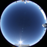 An all sky image of showing the two AST3 telescopes on the upper and right hand side. The bright spot at the bottom shows the Sun.